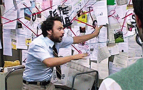 Charlie Day gesturing at an elaborate wall of papers and connecting strings